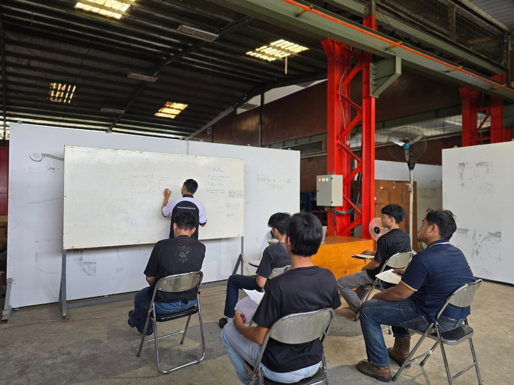 Seseorang menulis di papan tulis di depan peserta kegiatan Welding Training Center