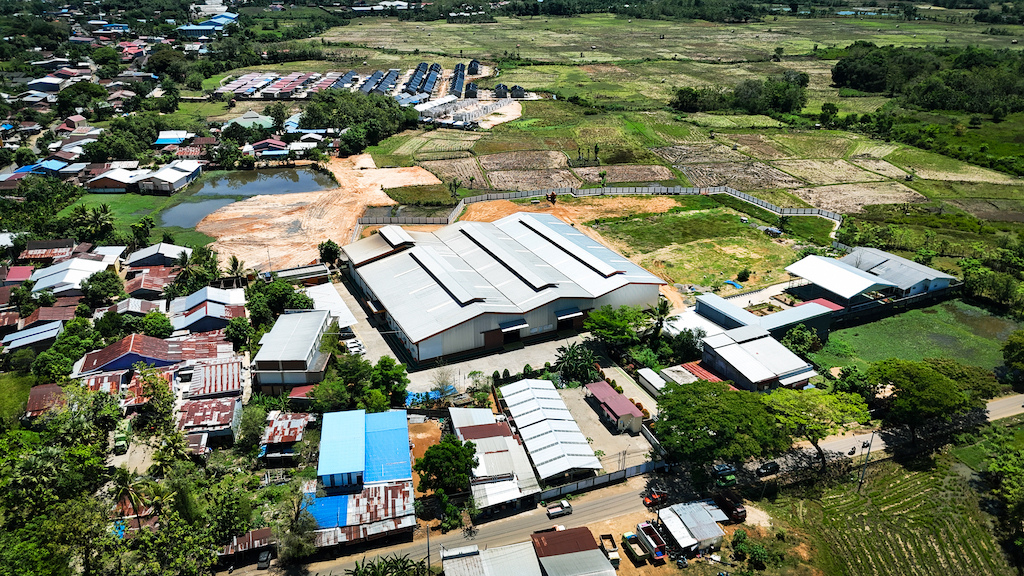Aerial view of an area with several buildings, roads, a pond, and surrounding green land